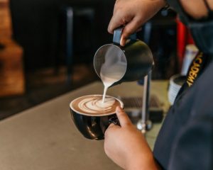 barista pouring milk into espresso drink